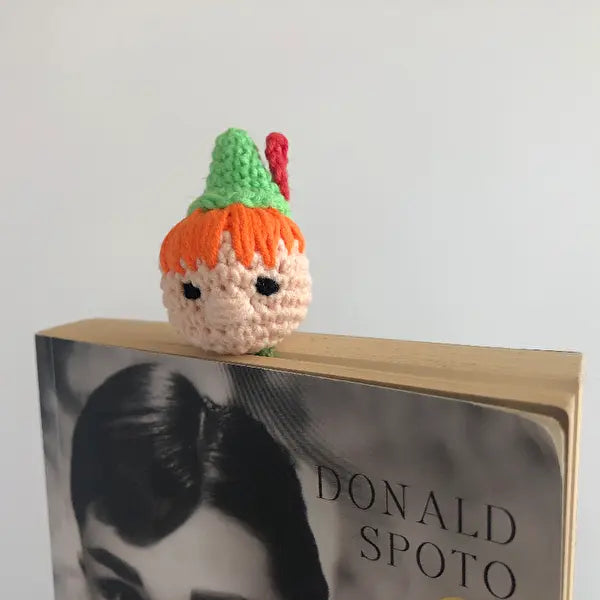 a crocheted doll sitting on top of a book