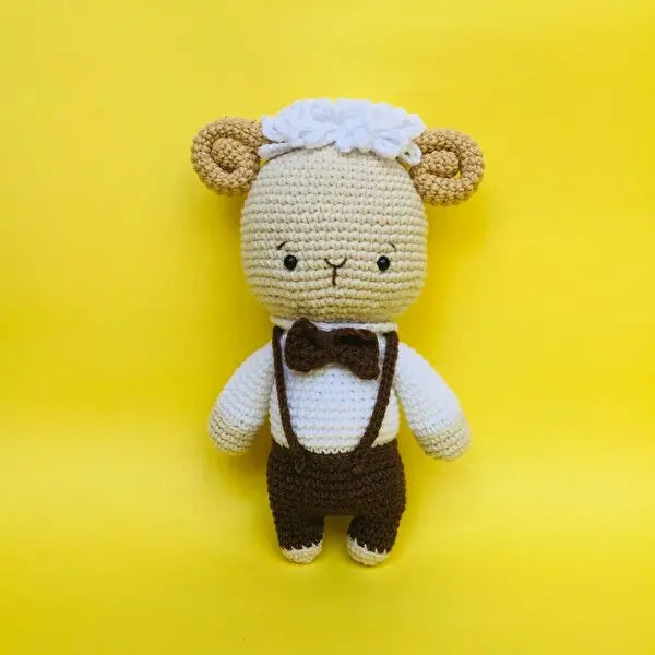 a crocheted teddy bear wearing a brown bow tie