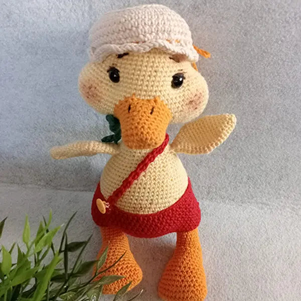 a crocheted stuffed duck wearing a red dress