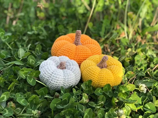 three crocheted pumpkins sitting in the grass