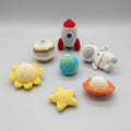 Collection of colorful crochet toys including a rocket, planets, and a star on a dark surface.
