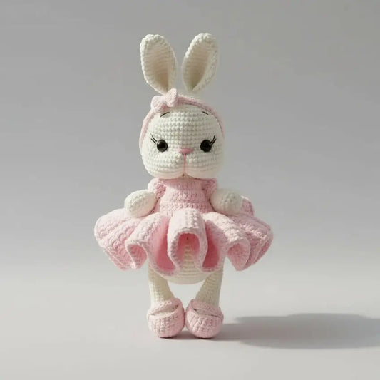 Crocheted white bunny in pink ballerina dress and shoes, standing on gray background