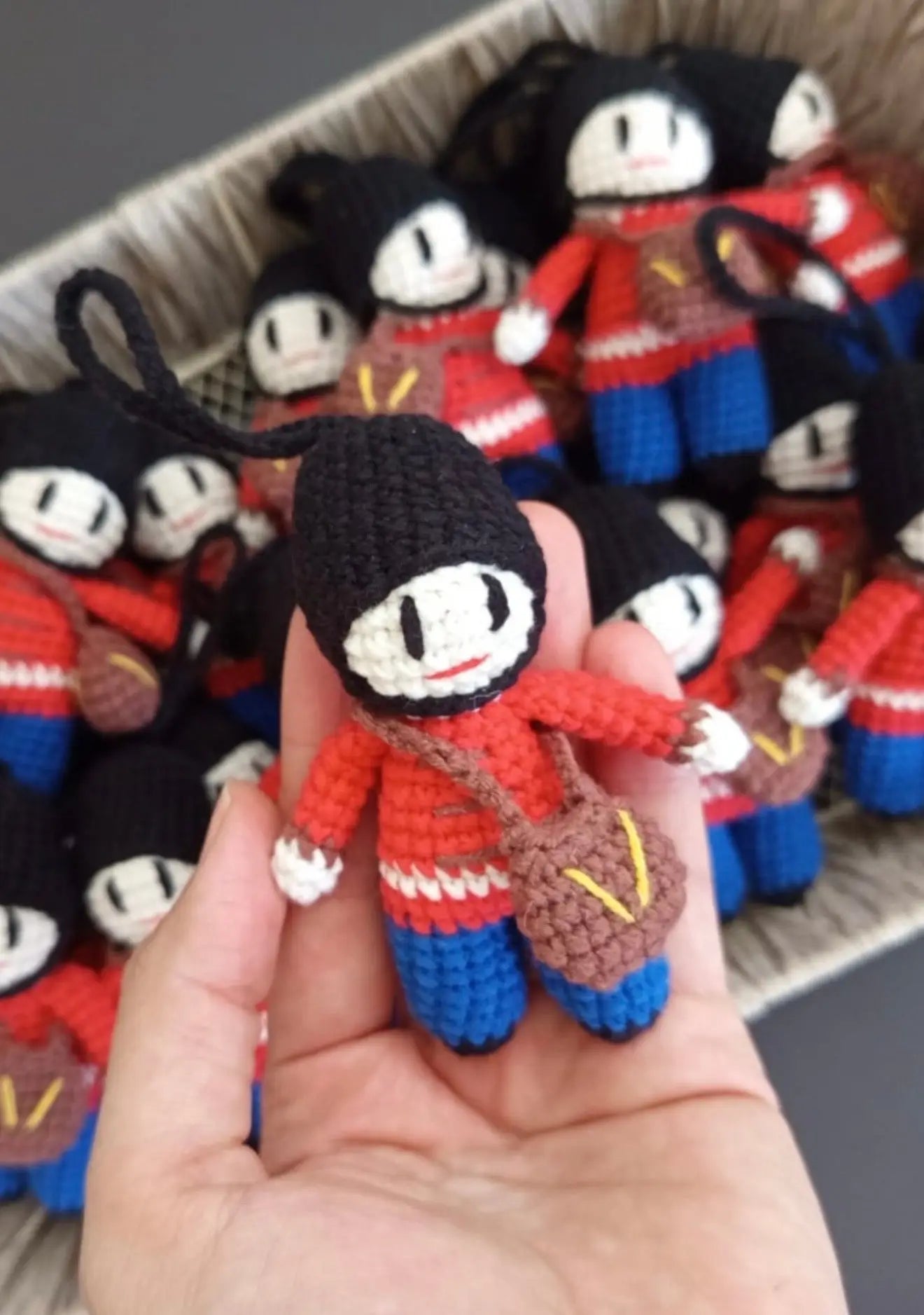 Crocheted mini dolls in red and blue uniforms with black heads, held in a hand
