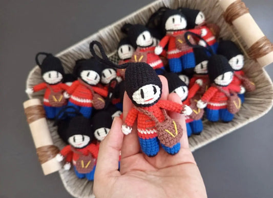 Crocheted dolls in red and blue uniforms with black hair in a basket and hand
