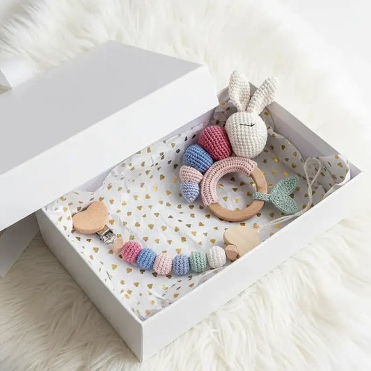 Handmade crochet baby toys in pastel colors, including bunny and teething ring, in gift box