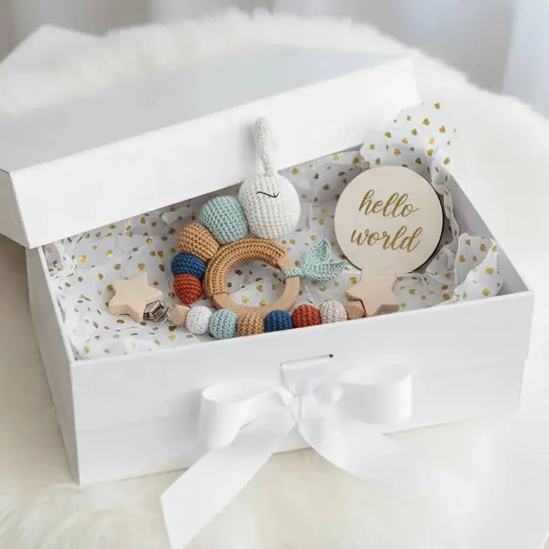 Handmade crochet baby toys and "hello world" tag in a white gift box with bow