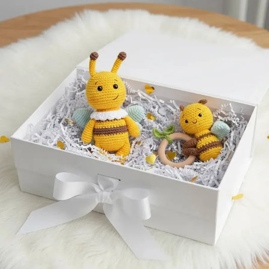 Crocheted yellow bees with cute faces nestled in a white gift box with white ribbon