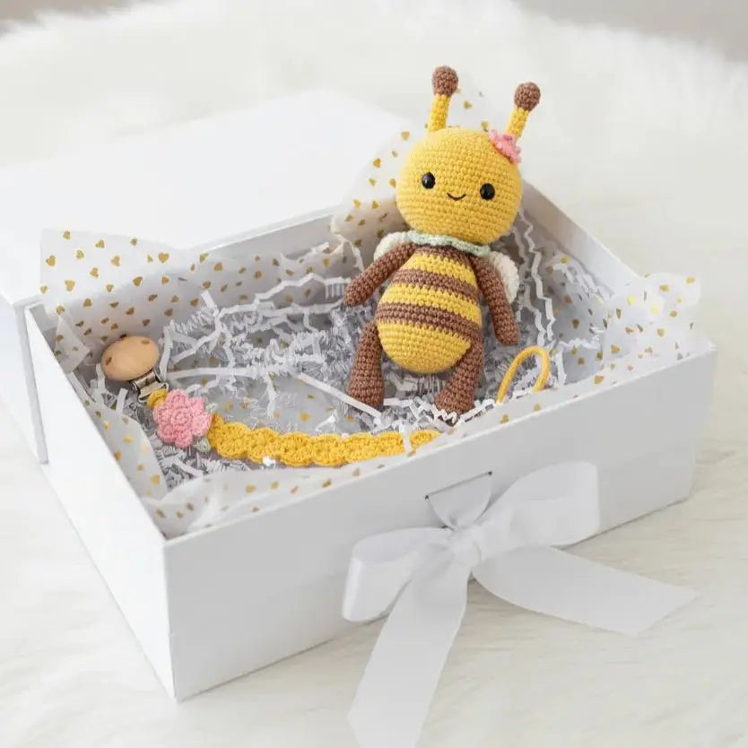 Crocheted bumble bee toy in a white gift box with flower and pacifier clip