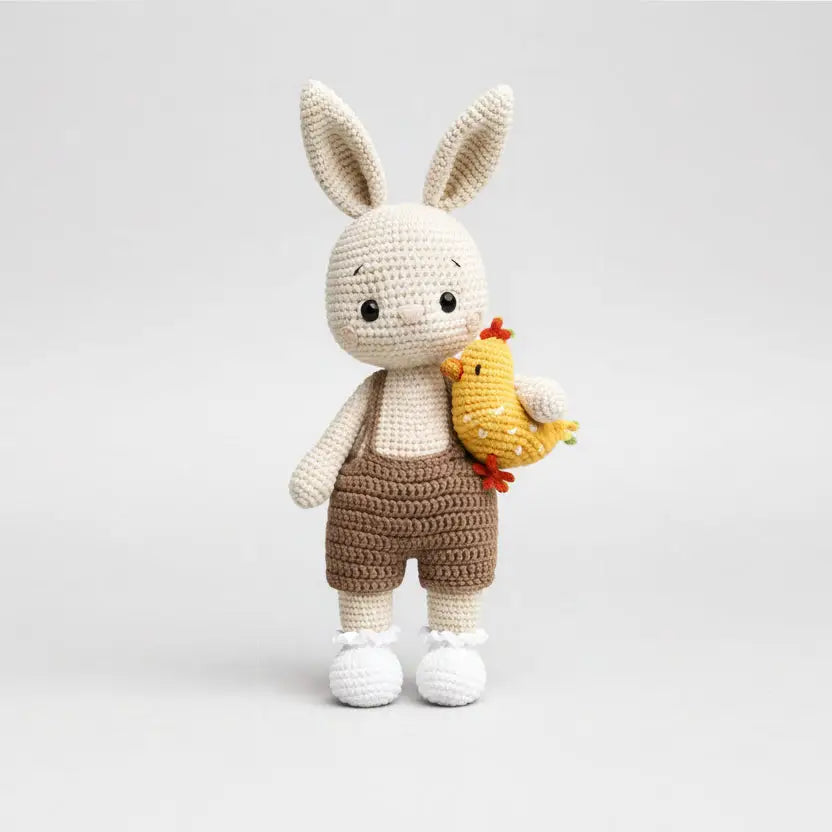 Crocheted bunny toy with a chick on a white background