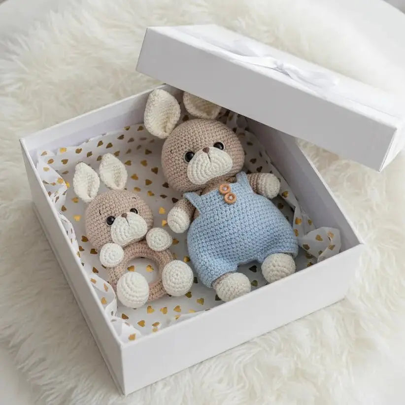 Two crocheted bunny dolls in a white gift box with gold heart-patterned lining