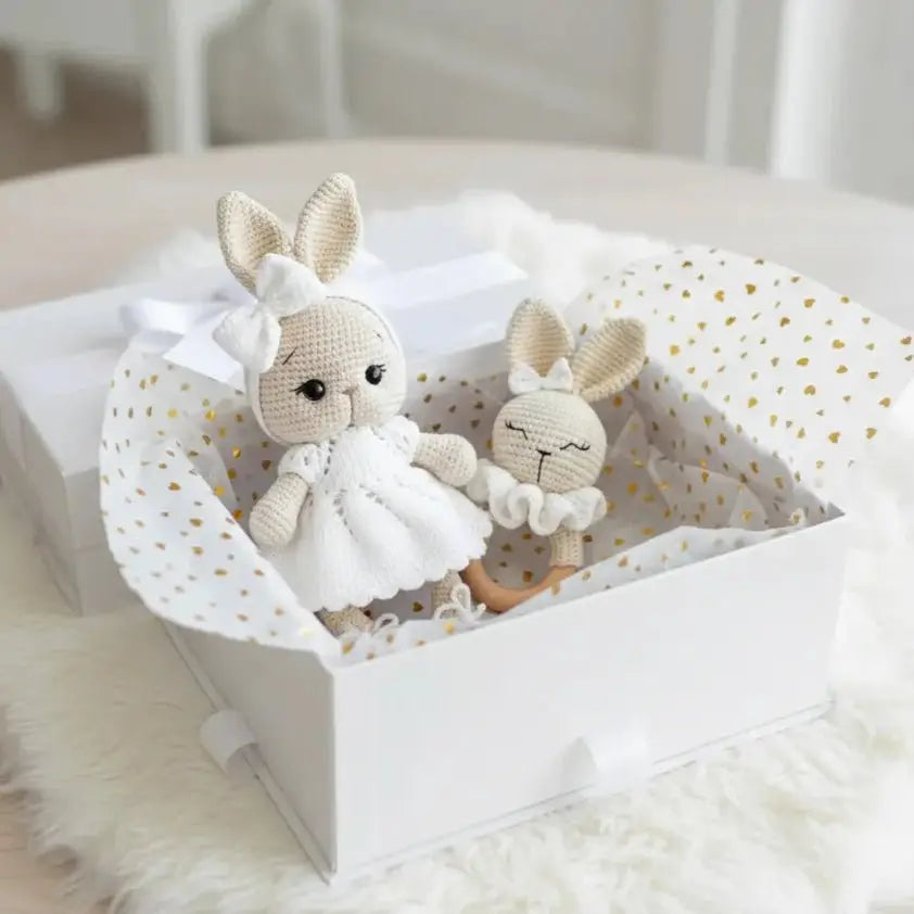 Two crocheted bunnies in white dress and sleepwear inside a polka-dot gift box