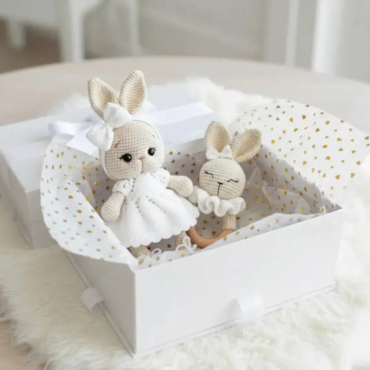 Two crocheted bunnies in white dress and sleepwear inside a polka-dot gift box