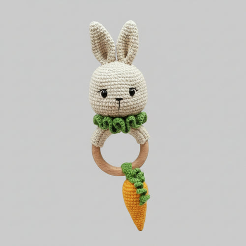 Crocheted bunny rattle with wooden ring and carrot-shaped toy, held by hand