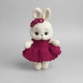 Crocheted white bunny with pink dress and flower headband, standing against gray background