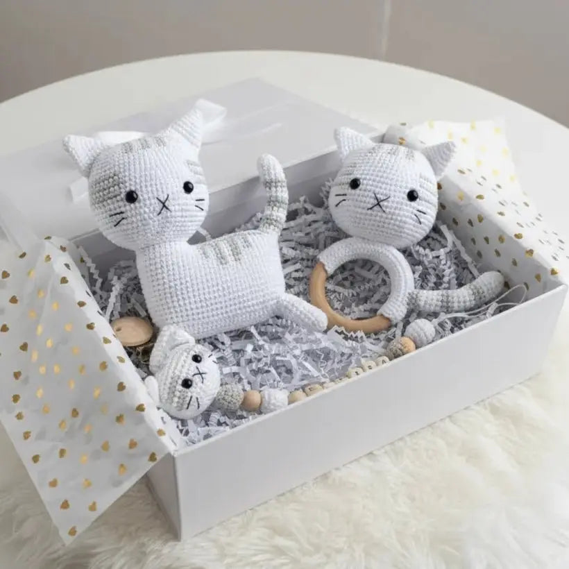 White crocheted cat toys and teething ring nestled in gift box with gold heart pattern