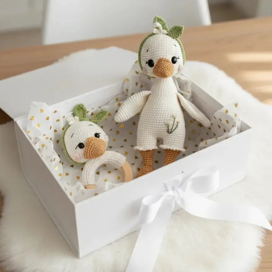 Two crocheted duck dolls in a white gift box with gold heart-patterned tissue paper
