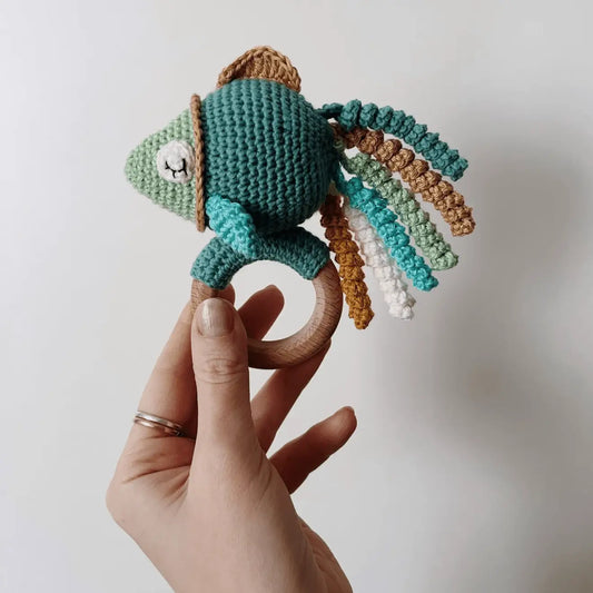 Crocheted chameleon teething ring with colorful curled yarn strands on wooden ring