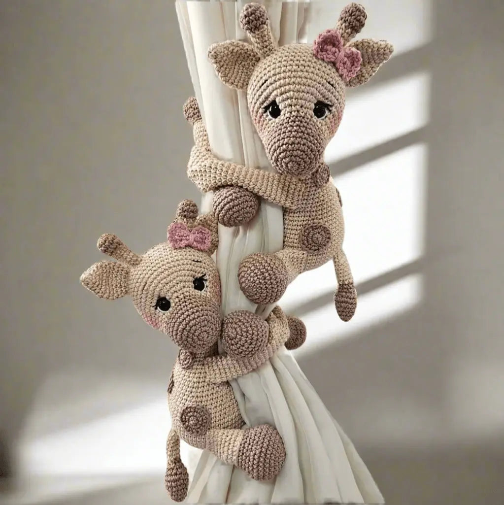 Two crocheted giraffes with pink bows, hugging a white curtain with soft shadows.
