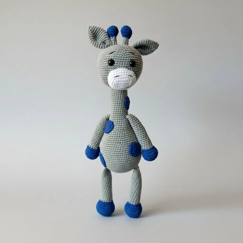 Crocheted giraffe plush toy with gray body and blue accents, standing upright with long neck and cute facial features