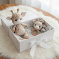 Crocheted giraffe and baby rattle in a white gift box on soft fur background