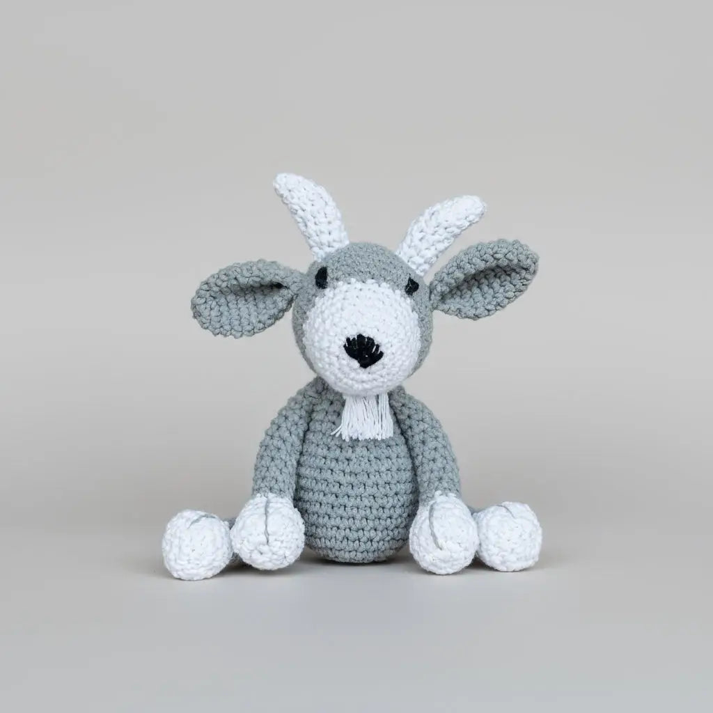 Crocheted gray and white bunny with long ears sitting against a neutral background