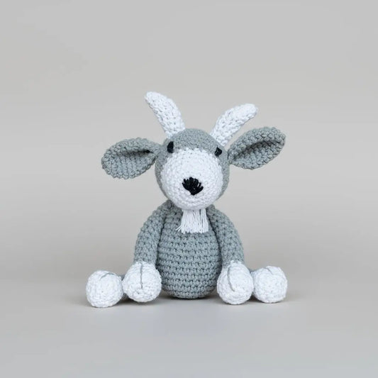 Crocheted gray and white bunny with long ears sitting against a neutral background