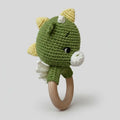 Green crocheted dinosaur baby rattle with wooden teething ring on white background