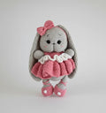 Crocheted gray bunny with pink bow and ruffled dress, standing on white background