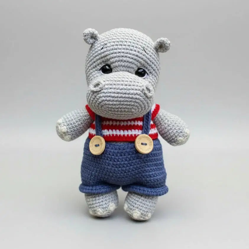 Crocheted gray hippo in red-white striped top and blue overalls with wooden buttons