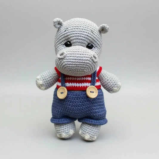 Crocheted gray hippo in red-white striped top and blue overalls with wooden buttons