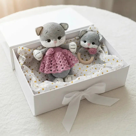 Two crocheted gray cats with pink sweater and wooden teething ring in a gift box with gold hearts