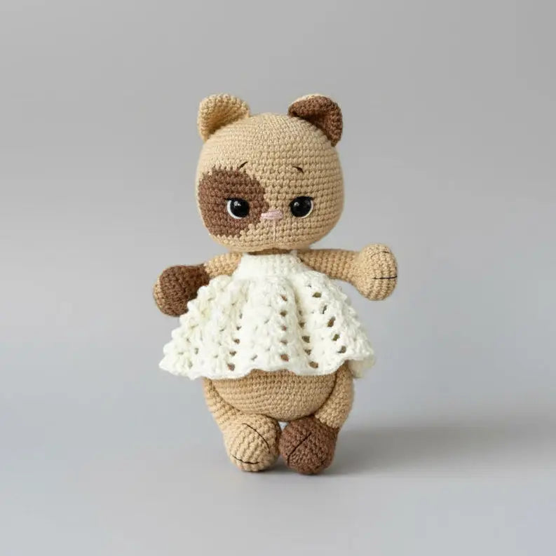 Crocheted teddy bear with brown and beige yarn, wearing a white lacy dress