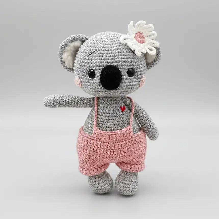 Crocheted koala stuffed animal in gray and pink with white flower