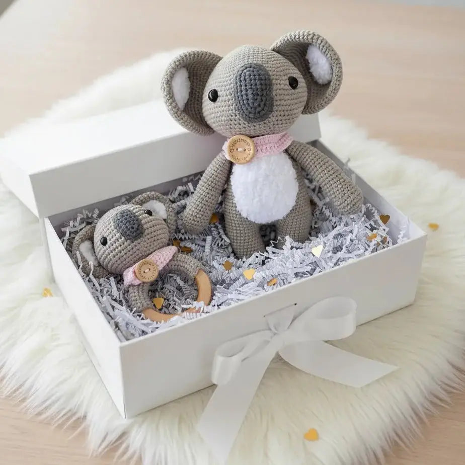 Crocheted koala stuffed animals in a white gift box with ribbon and shredded paper