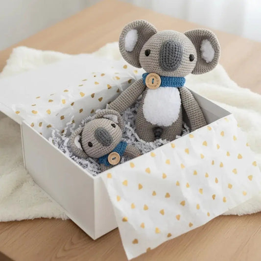 Two crocheted koalas in a polka dot gift box with white crinkle paper