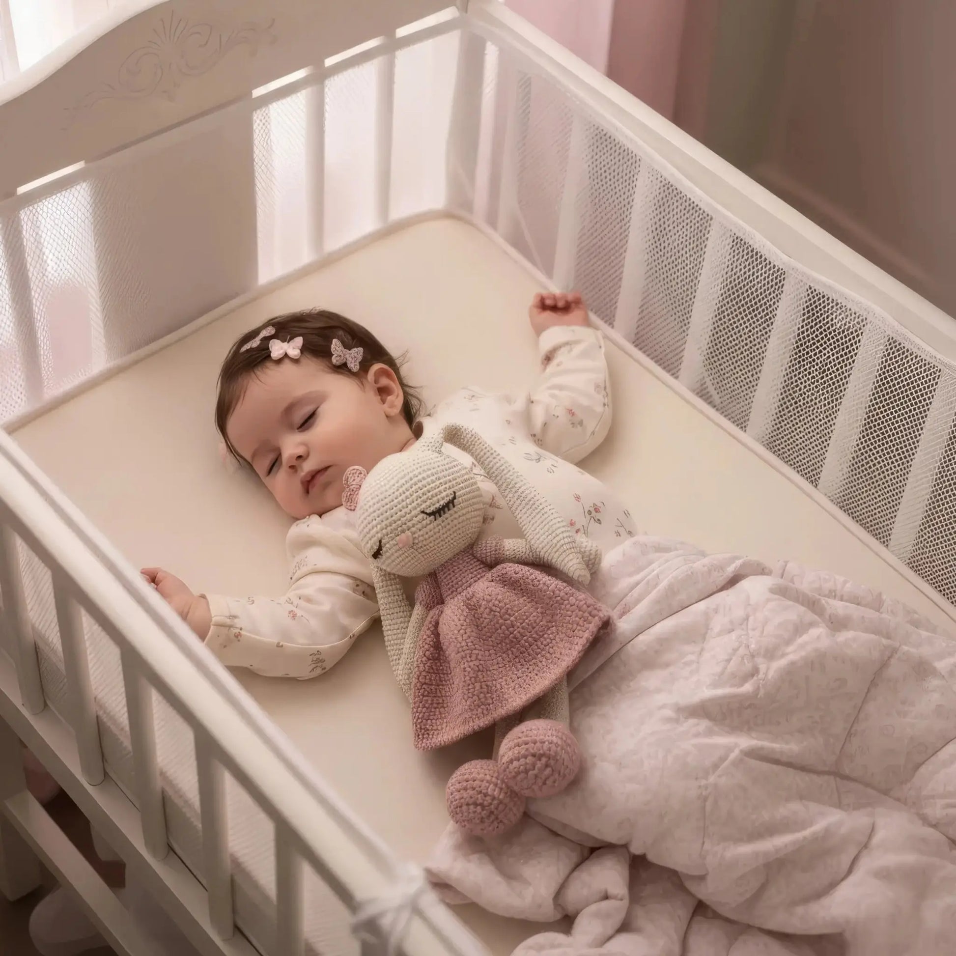 Peaceful baby sleeping in white crib with pink bunny stuffed animal and butterfly hair clips