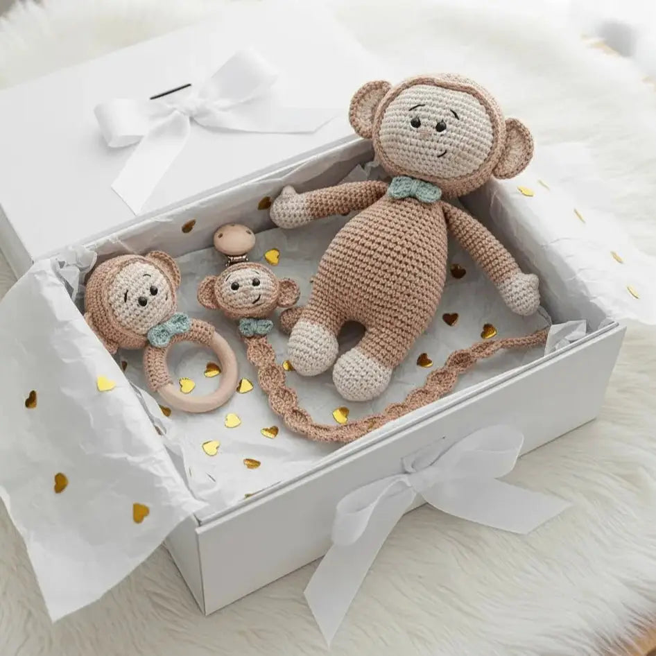 Crocheted monkey toys in a white gift box with gold heart confetti