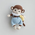 Crocheted monkey stuffed animal in blue overalls with white collar and banana