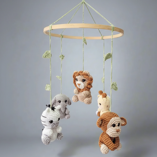 Crocheted baby mobile with safari animals hanging from wooden ring with green leaves