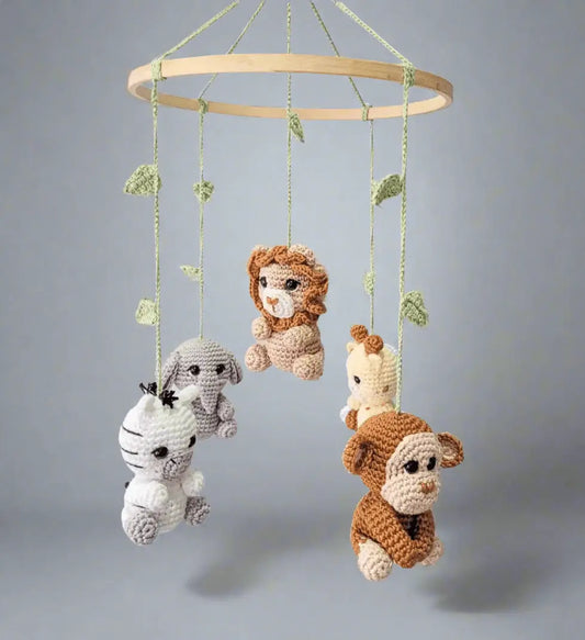 Crocheted baby mobile with safari animals hanging from wooden ring with green leaves