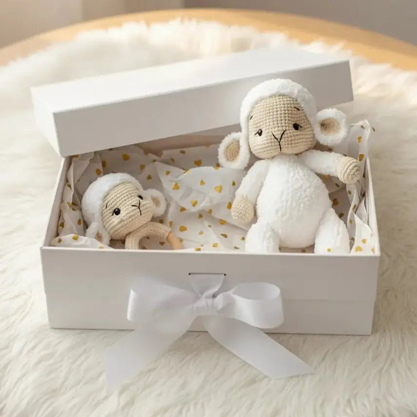 Crocheted lamb stuffed animals in a white gift box with gold polka dot tissue paper