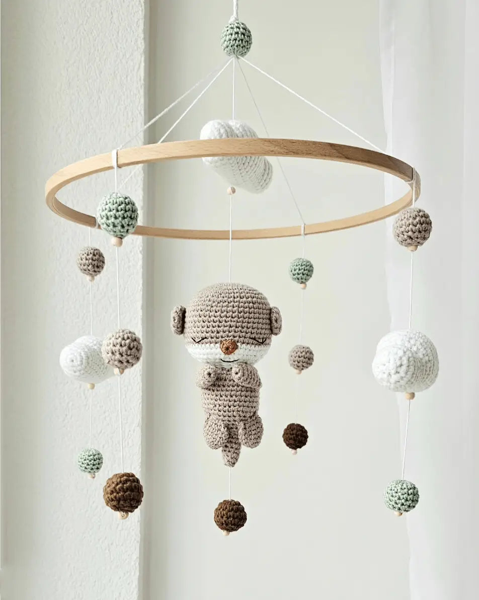 Crocheted baby mobile with hanging spheres and a cute sleepy character in soft neutrals