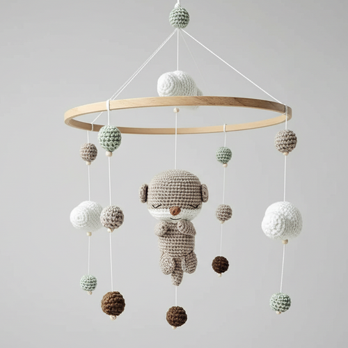 Crocheted baby mobile with hanging spheres and a cute sleepy character in soft neutrals