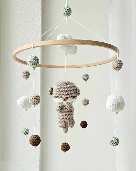 Crocheted baby mobile with hanging spheres and a cute sleepy character in soft neutrals