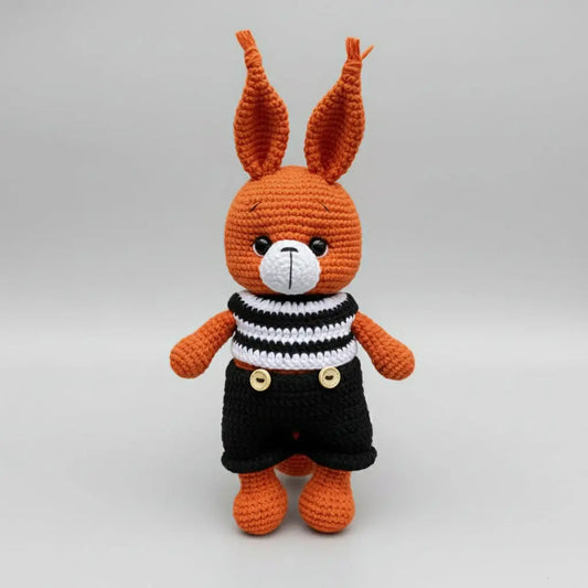 Orange crocheted bunny in striped shirt and black overalls with buttons