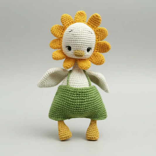 Crocheted sunflower doll with white body, yellow petals, and green skirt on gray background