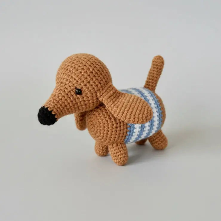 Crocheted brown dachshund with blue and white striped sweater on gray background