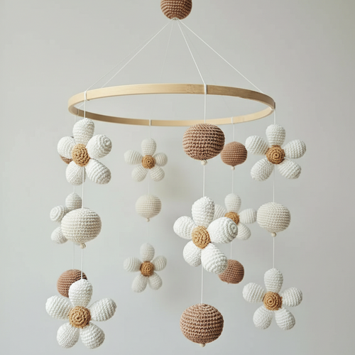 Crocheted baby mobile with white and brown spheres and daisy-like flowers hanging from wooden ring