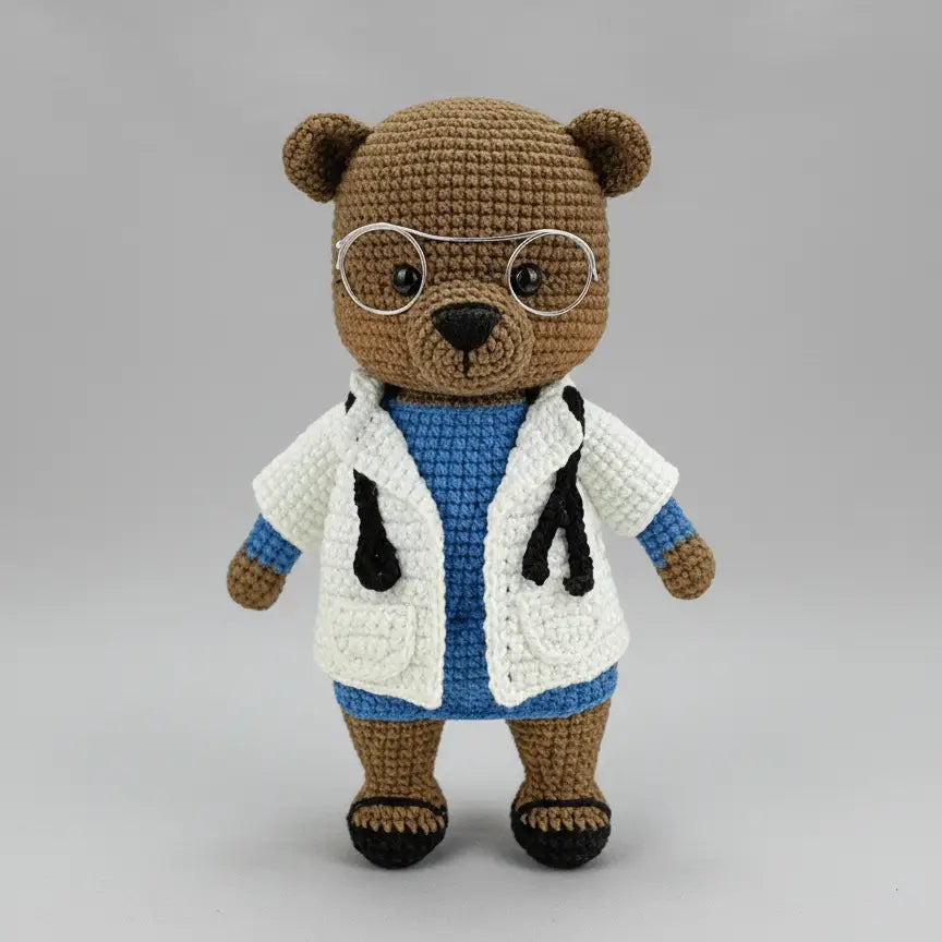 Crocheted teddy bear wearing glasses and a doctor's white lab coat with stethoscope