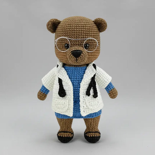 Crocheted teddy bear wearing glasses and a doctor's white lab coat with stethoscope